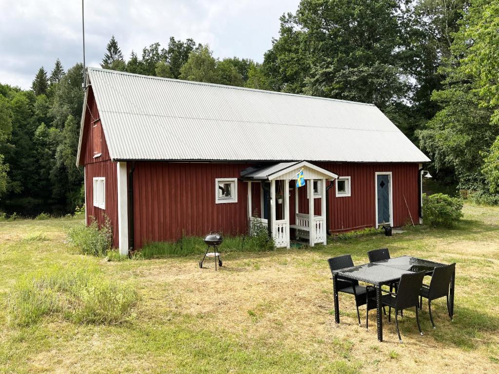 Red little cottage located in the forest and next to a small lake