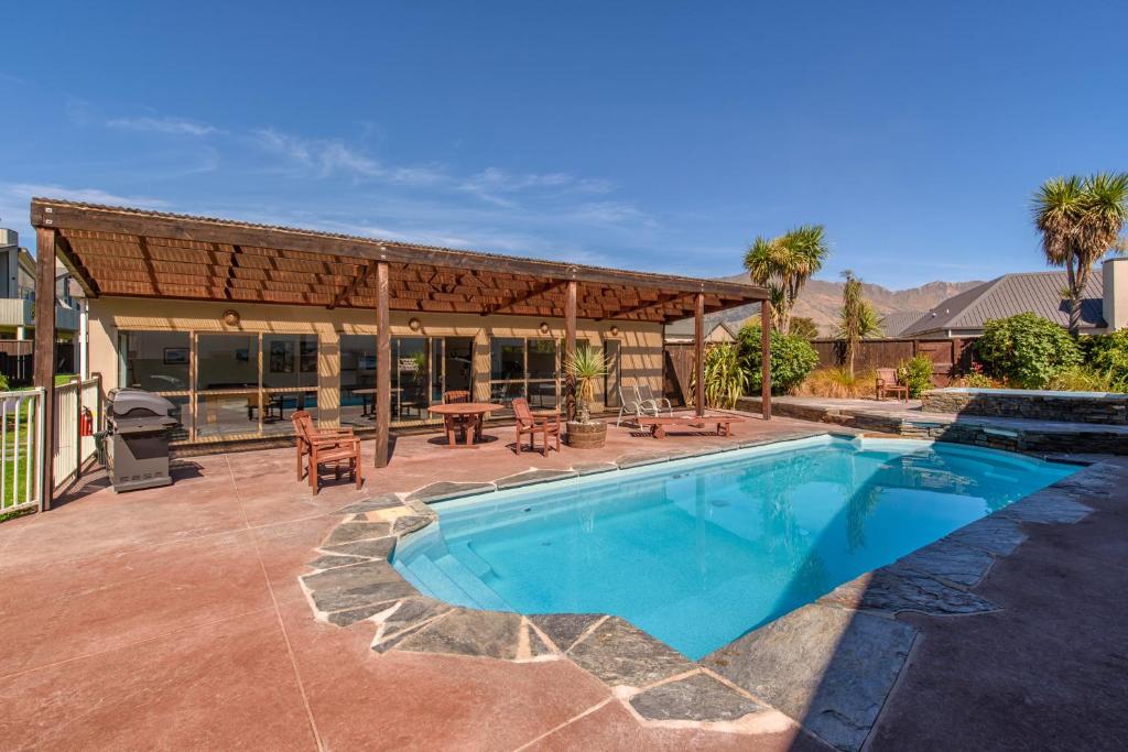 a swimming pool with a blue chair and a blue umbrella, Deluxe Apartments Wanaka in Wanaka