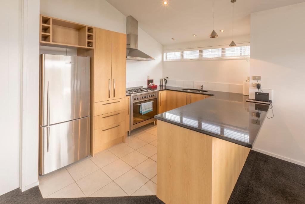 a kitchen with stainless steel appliances and wood cabinets, Deluxe Apartments Wanaka in Wanaka