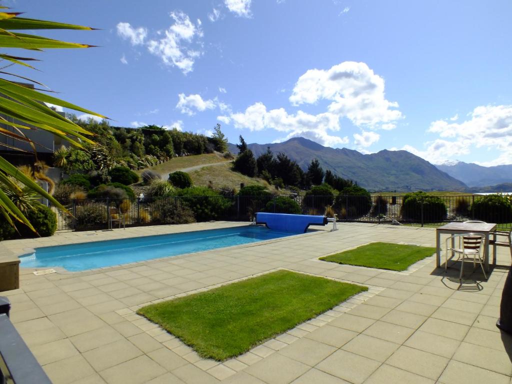a patio area with a pool and lawn chairs, Deluxe Apartments Wanaka in Wanaka