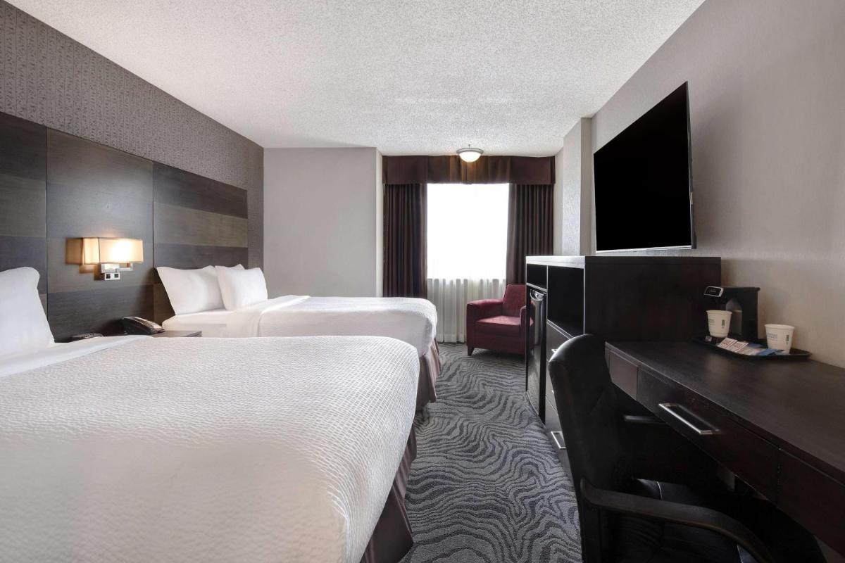 Guest room with two beds and a desk at Days Inn by Wyndham Calgary South