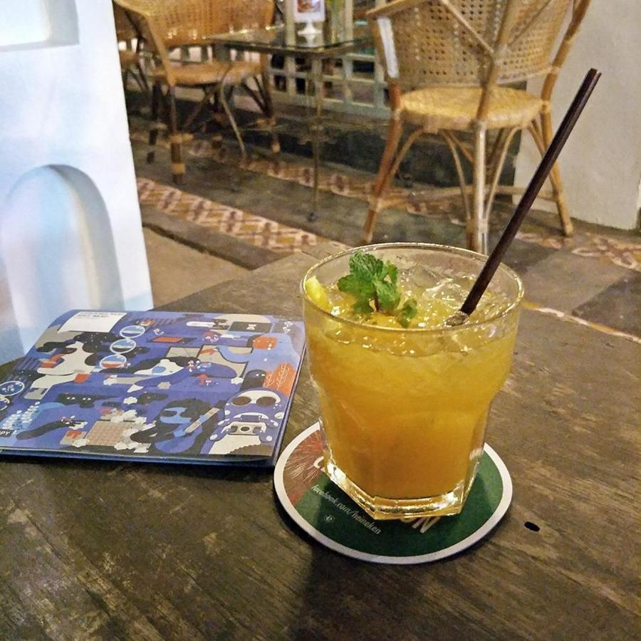 Short clear glass with orange drink and brown straw rests on coaster at pet-friendly Villa Duangchampa in Chiang Mai.