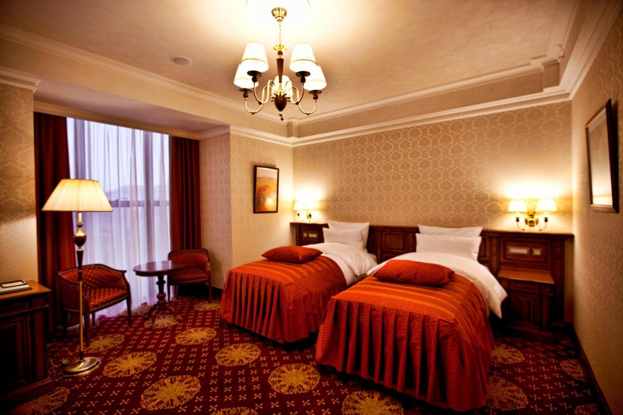Two twin beds with red bedspreads and white pillows occupy room at dog-friendly Multi Grand Pharaon Hotel in Agveran.