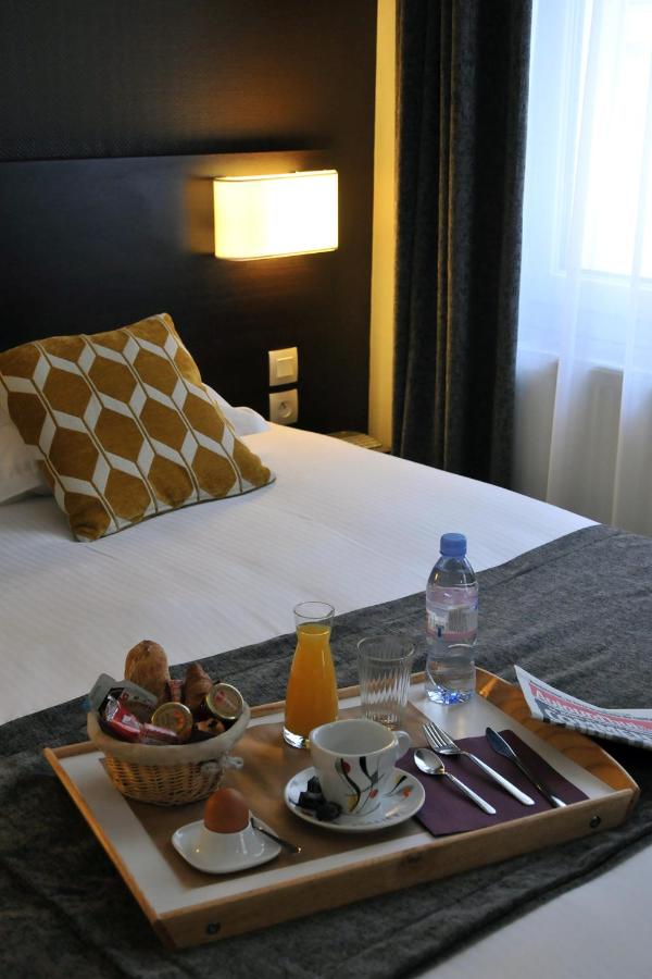 Wooden breakfast tray with white cup and glass sits at pet-friendly Hôtel Des Quatrans in Caen.