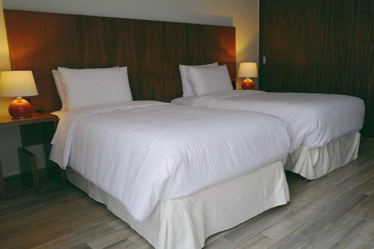 Two white twin beds with wooden headboard sit at dog-friendly Villas La Ceiba in Playa del Carmen.