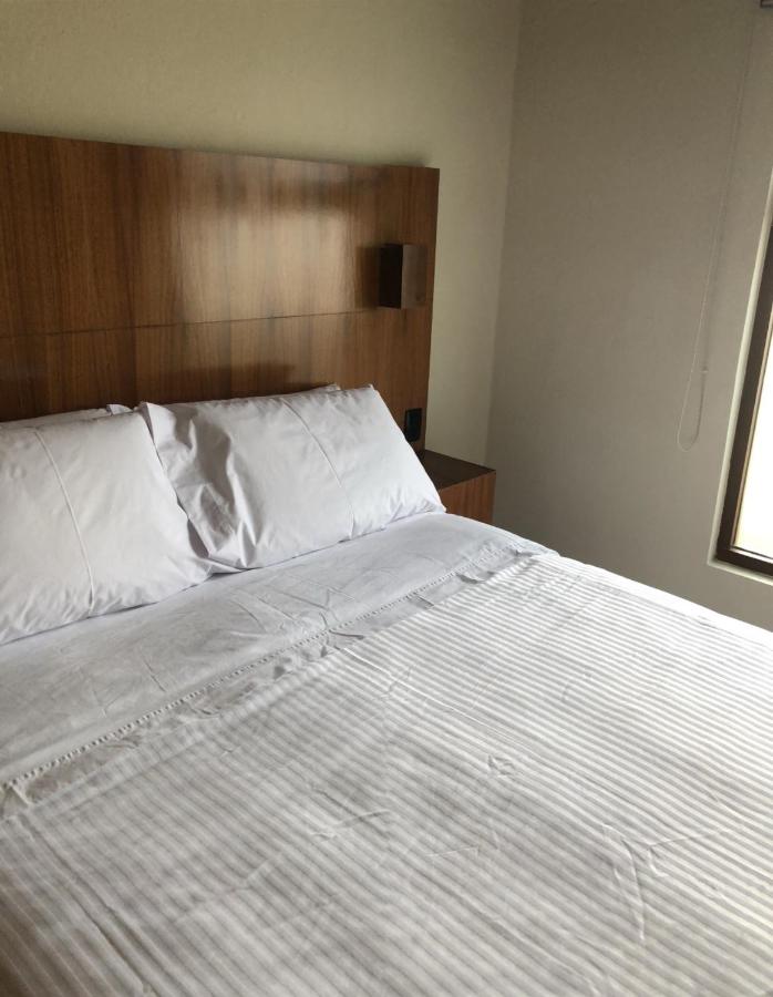 White bed with wooden headboard sits at dog-friendly Villas La Ceiba in Playa del Carmen.
