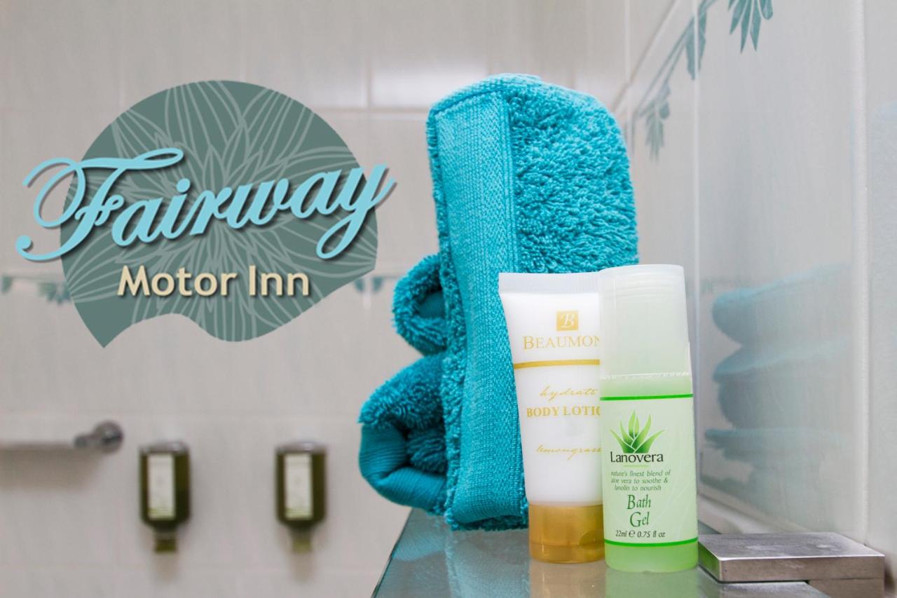 Turquoise towels and white and green toiletry bottles rest on glass shelf at dog-friendly Fairway Motor Inn in Pambula.