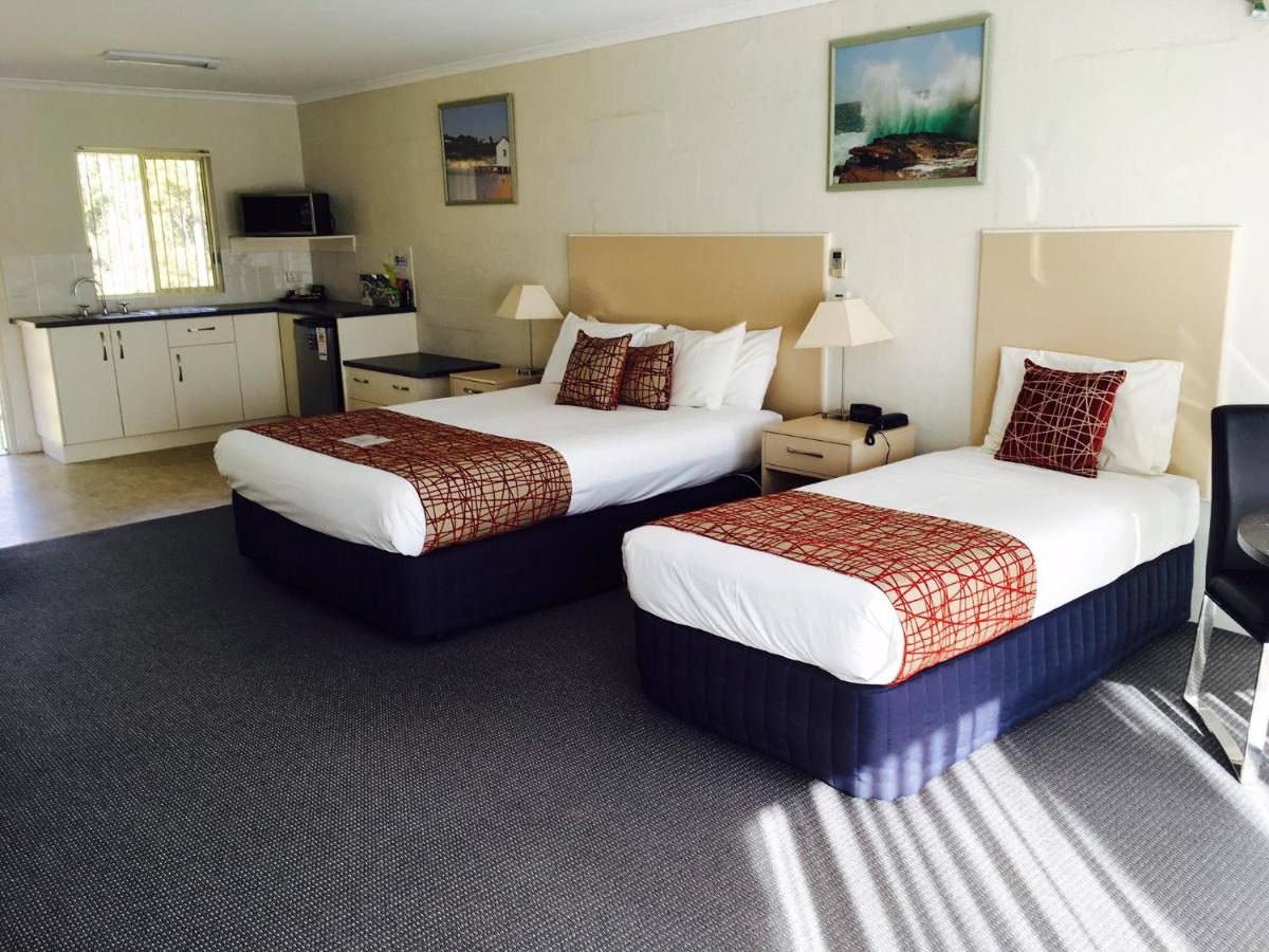 Two beds with white linens and red patterned runners sit at dog-friendly Fairway Motor Inn in Pambula.