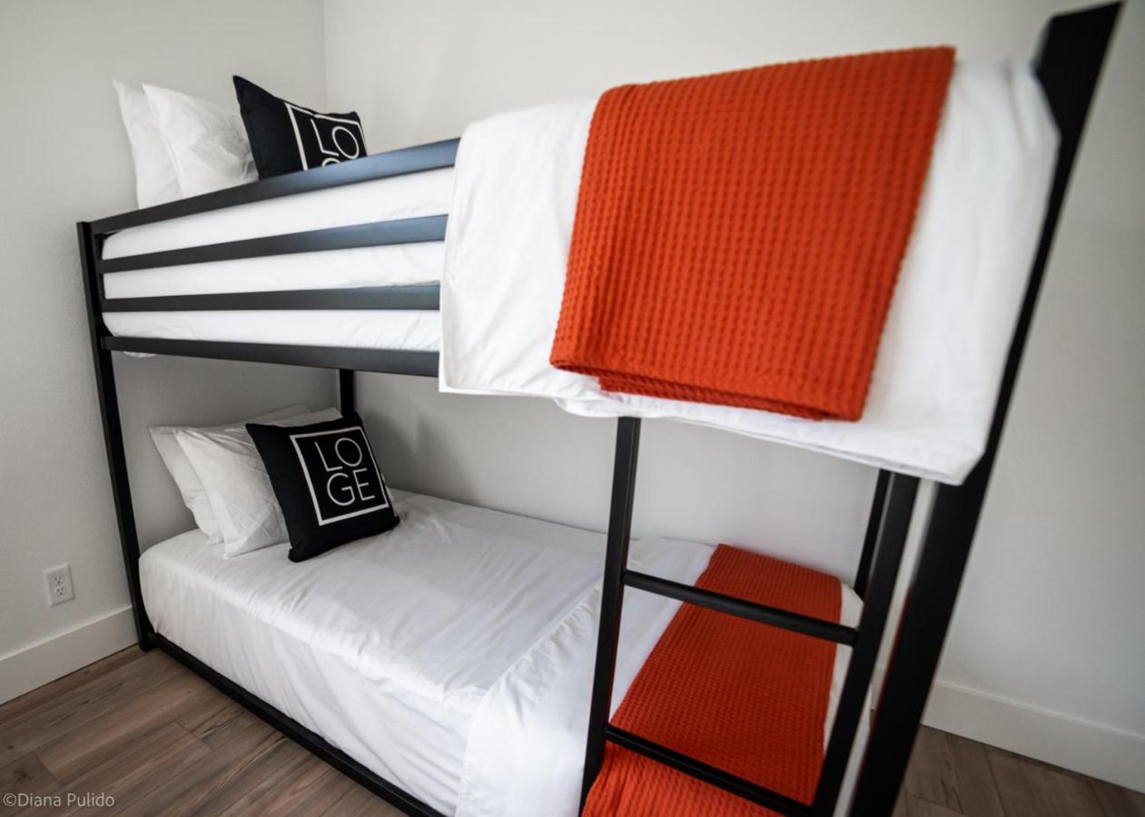 Black metal bunk bed with white sheets and orange blankets sits at dog-friendly LOGE Leavenworth in Leavenworth, WA.