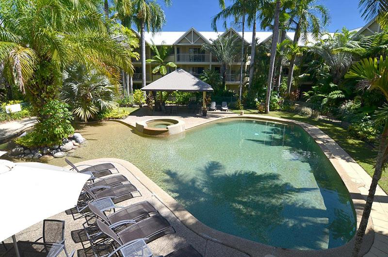 White umbrella and dark lounge chairs sit at dog-friendly Port Douglas Sands Resort in Port Douglas.
