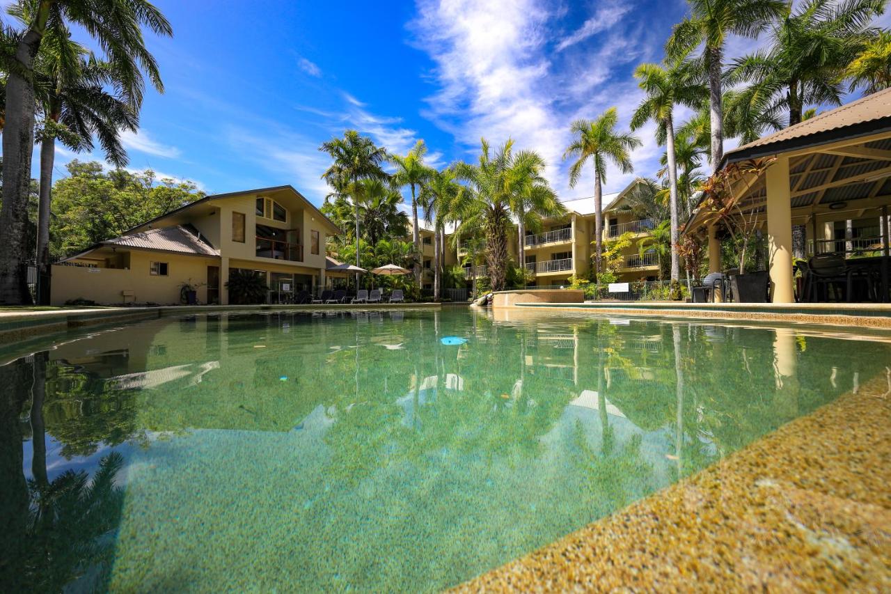 Beige two-story building with balconies stands beside pool at dog-friendly Port Douglas Sands Resort in Port Douglas.