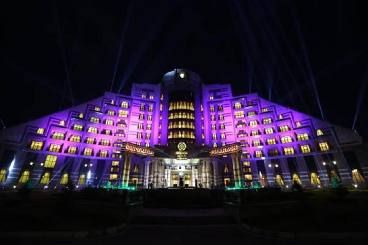 Large purple-lit multi-story hotel stands at dog-friendly Multi Grand Pharaon Hotel in Agveran.