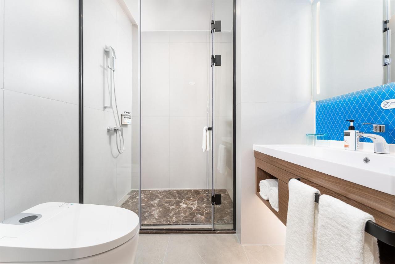 White toilet sits beside glass shower at dog-friendly Holiday Inn Express Nanning Convention And Exhibit by IHG in Nanning.