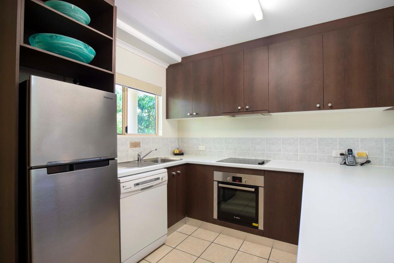 Stainless steel refrigerator beside white dishwasher and brown cabinets sits at pet-friendly Port Douglas Sands Resort in Port Douglas.