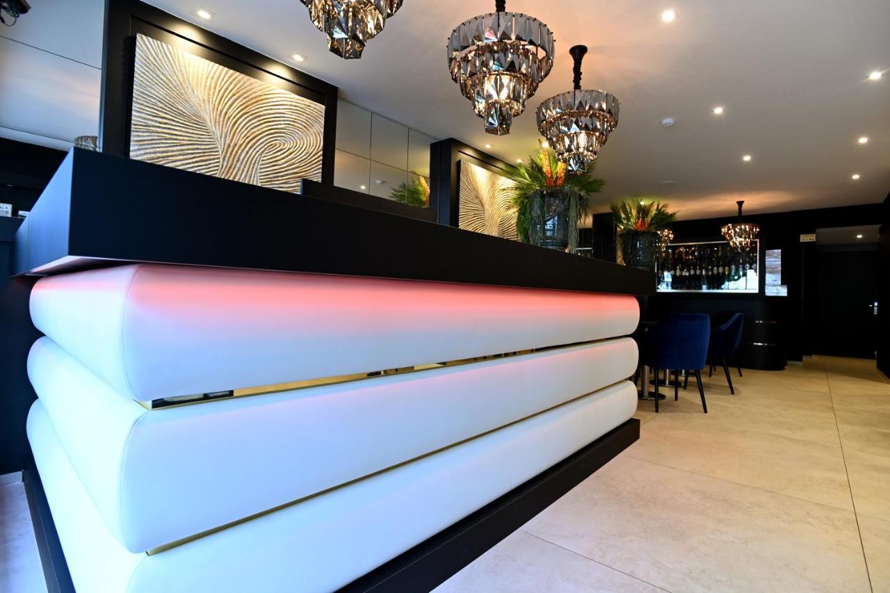White tufted reception counter with black top and pink LED lighting sits at dog-friendly Hôtel Des Quatrans in Caen.