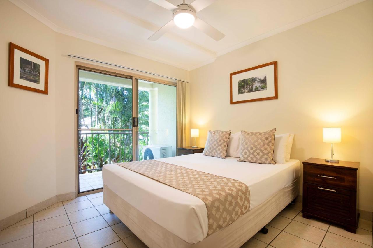 Bed with white sheets, beige pillows sits by sliding door at dog-friendly Port Douglas Sands Resort in Port Douglas.