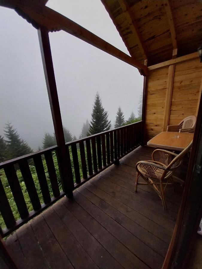 Dark wooden balcony with wicker chairs sits at dog-friendly Ayder Cise Dag Evleri in Camlihemsin.