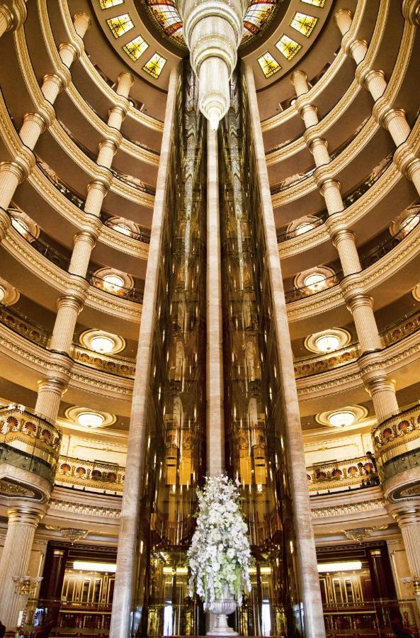 Tall mirrored glass elevator shafts stand in ornate gold-and-ivory atrium at dog-friendly Multi Grand Pharaon Hotel in Agveran.