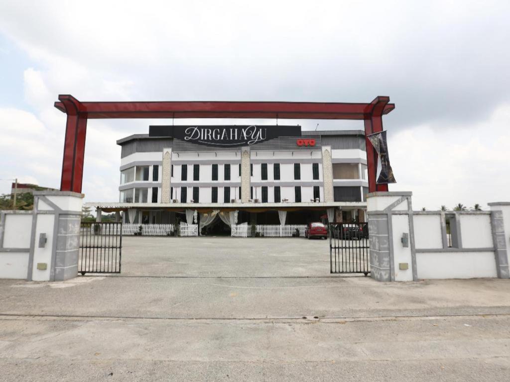 White three-story building with black Dirgahayu sign stands at pet-friendly OYO 89888 Dz Residence Guest House in Kota Bharu.