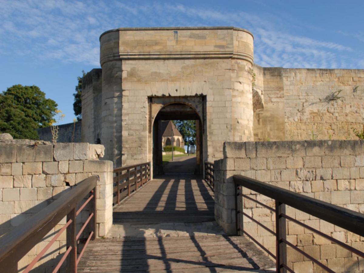 Beige stone gate with wooden bridge stands at dog-friendly Hôtel Des Quatrans in Caen.