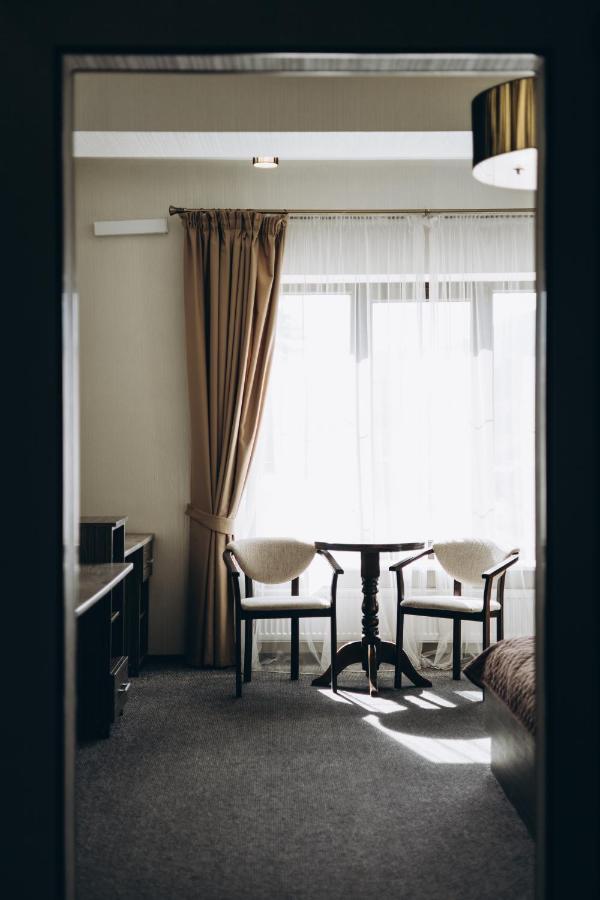 Two white cushioned wooden chairs sit at pet-friendly Hotel Complex Dvir Kniazhoiy Korony in Slavske.