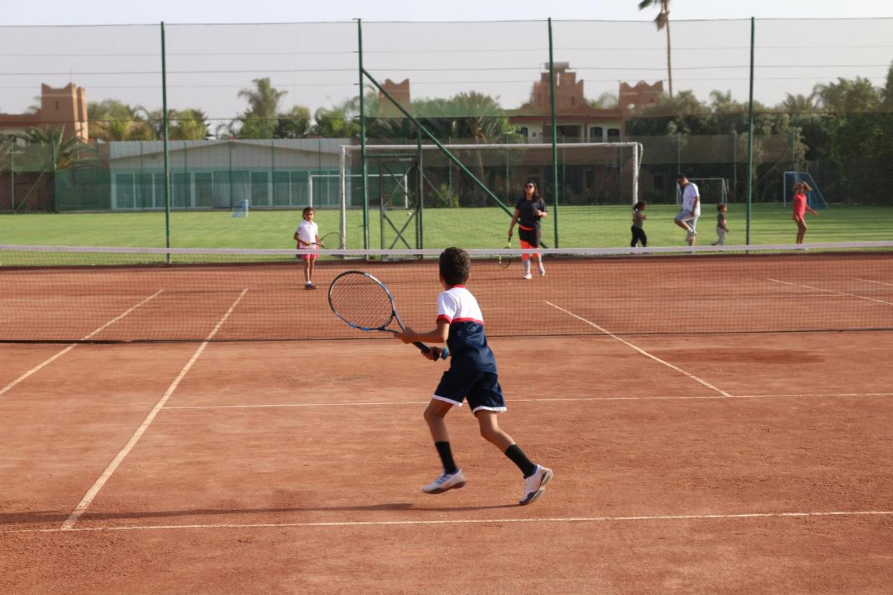 Boy in navy shirt and shorts with racket runs toward net at dog-friendly Le Domaine Limoune in Oulad Teima.