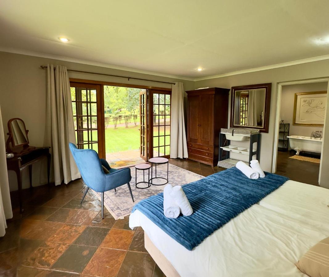 Blue armchair faces open doors at dog-friendly Luxury Country Retreat Hot Tub & Farm Views in Dullstroom.