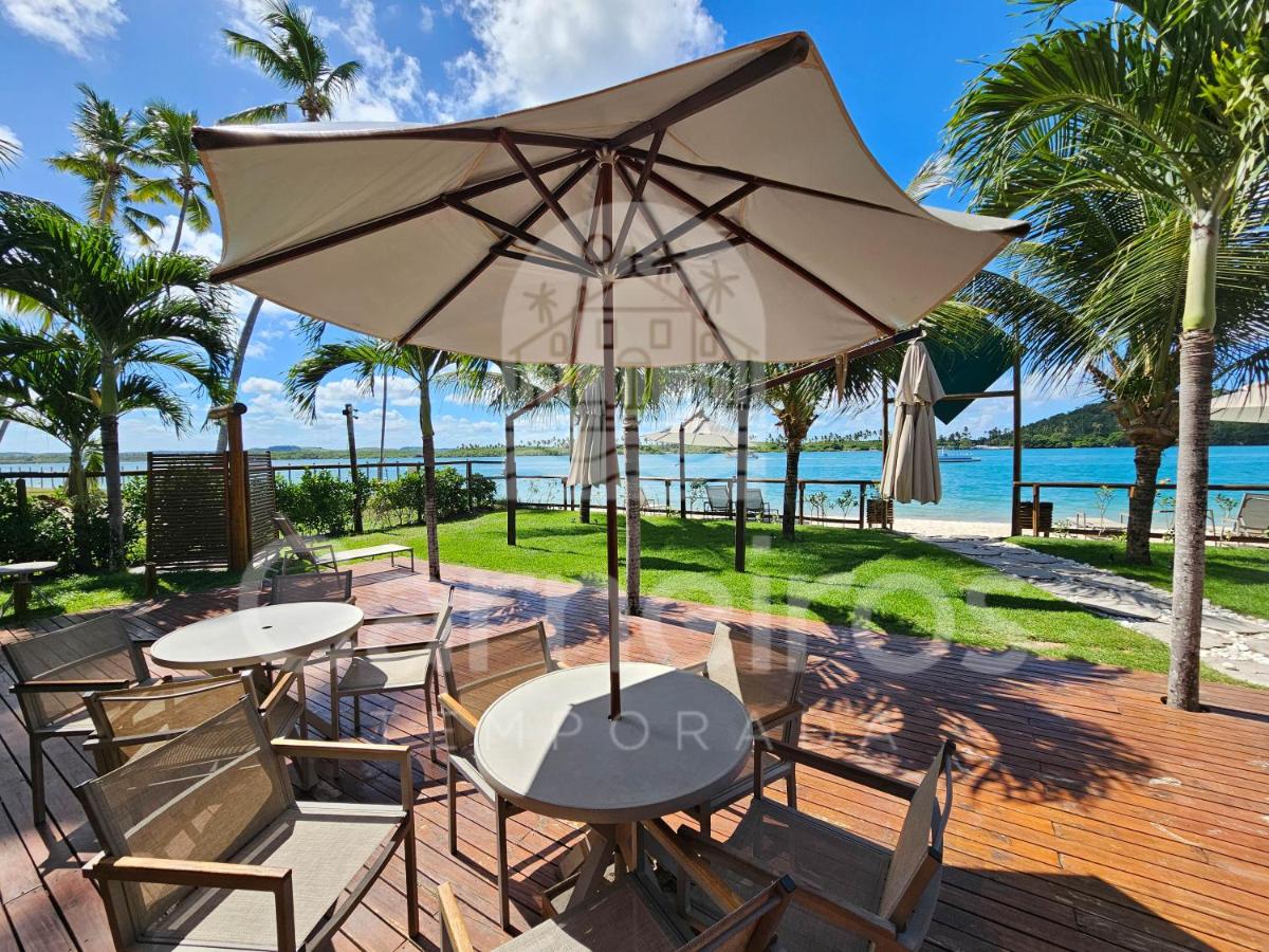 Beige umbrella with wooden ribs shades a round table at dog-friendly Amura Carneiros in Praia dos Carneiros.