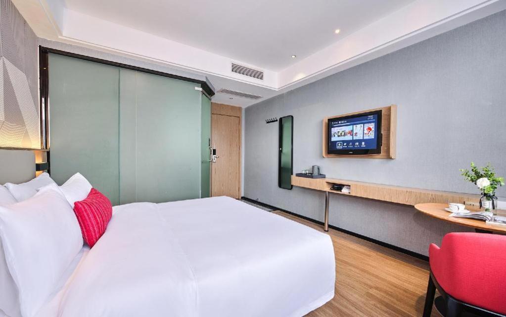 White bed with red pillow sits at dog-friendly Borrman Hotel Changsha Hunan Biological Electromechanical College in Xingsha.