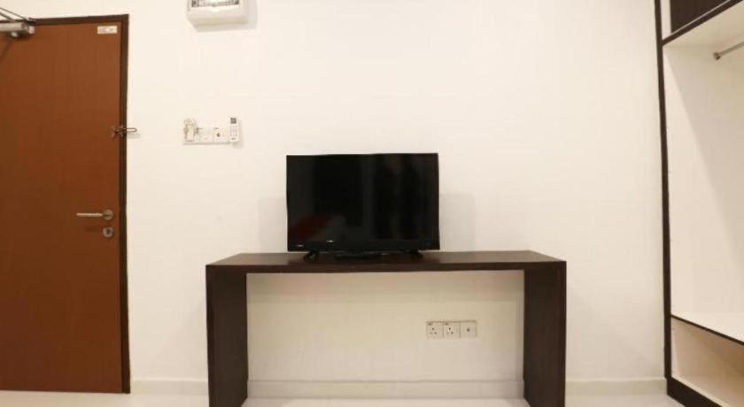 A black television on dark brown console sits at dog-friendly OYO 89888 Dz Residence Guest House in Kota Bharu.