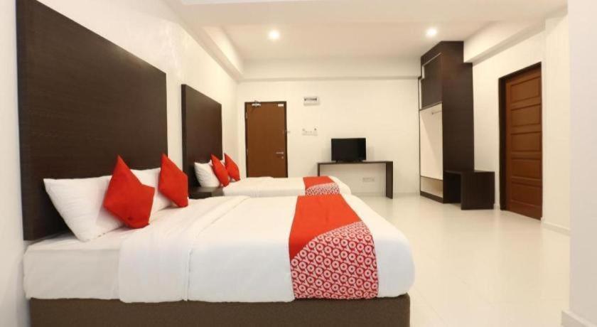 White beds, red pillows and patterned runners sit at pet-friendly OYO 89888 Dz Residence Guest House in Kota Bharu.