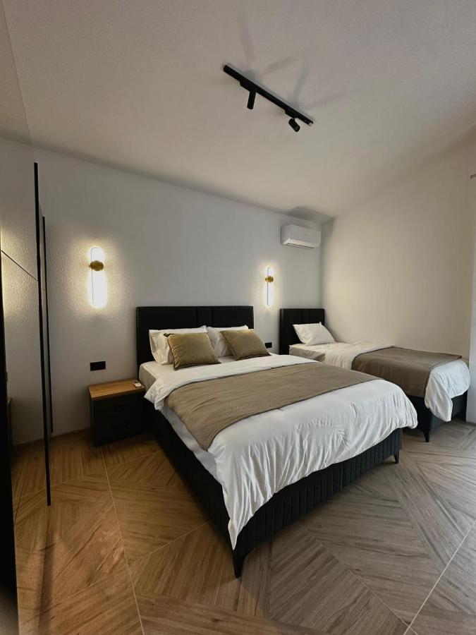 Black bed with white linens and beige throw sits at dog-friendly Casa Mila Apartments & Bungalows in Ulcinj.