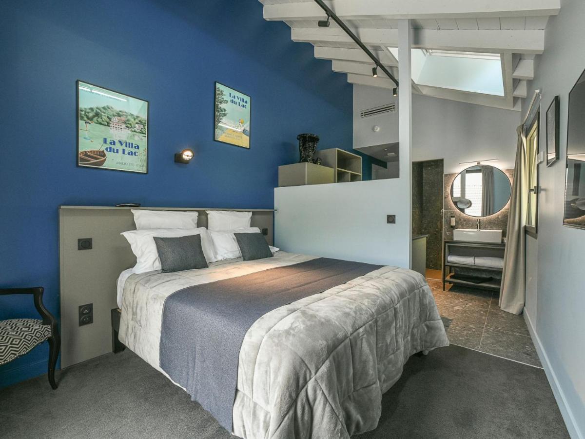 A gray bed with white pillows and dark throw sits at dog-friendly La Villa du Lac in Aiguebelette-le-Lac.