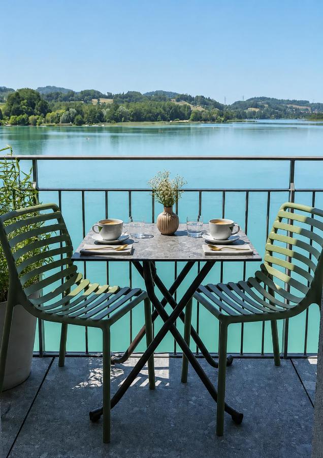 Two green slatted chairs flank a marble-top table at dog-friendly La Villa du Lac in Aiguebelette-le-Lac.