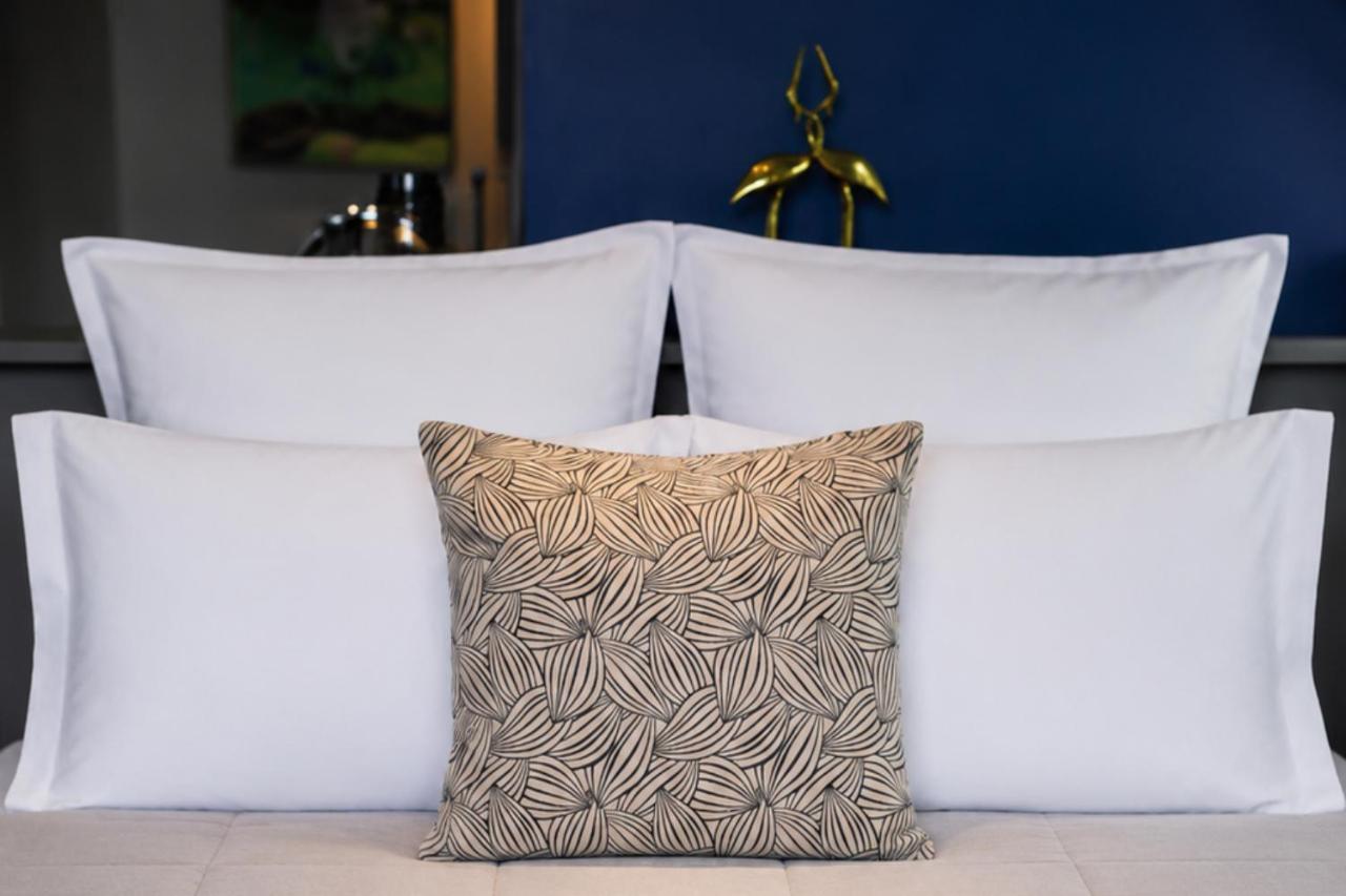 Beige patterned square pillow rests on white pillows at dog-friendly La Villa du Lac in Aiguebelette-le-Lac.