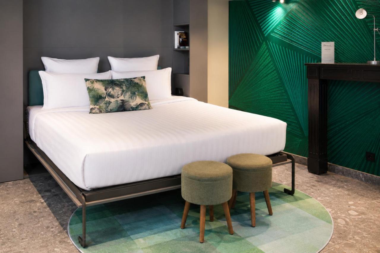 White bed with white pillows and green palm-print cushion sits at dog-friendly La Villa du Lac in Aiguebelette-le-Lac.