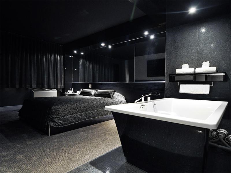 Black bathtub with white interior sits beside dark bed at dog-friendly Complexe Hotelier Le 55 in Becancour, QC.