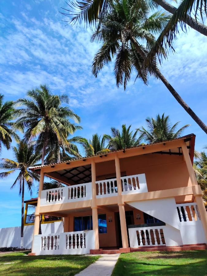 Peach-and-white two-story building with white balconies and columns sits at pet-friendly Hotel Y Restaurante Punta Corona in Acajutla.
