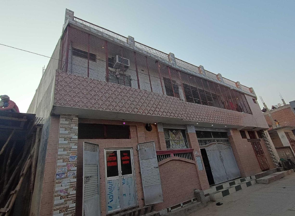 Pink tiled two-story building with metal shutters stands at dog-friendly OYO Hotel 44676 Jyotish House in Ayodhya.