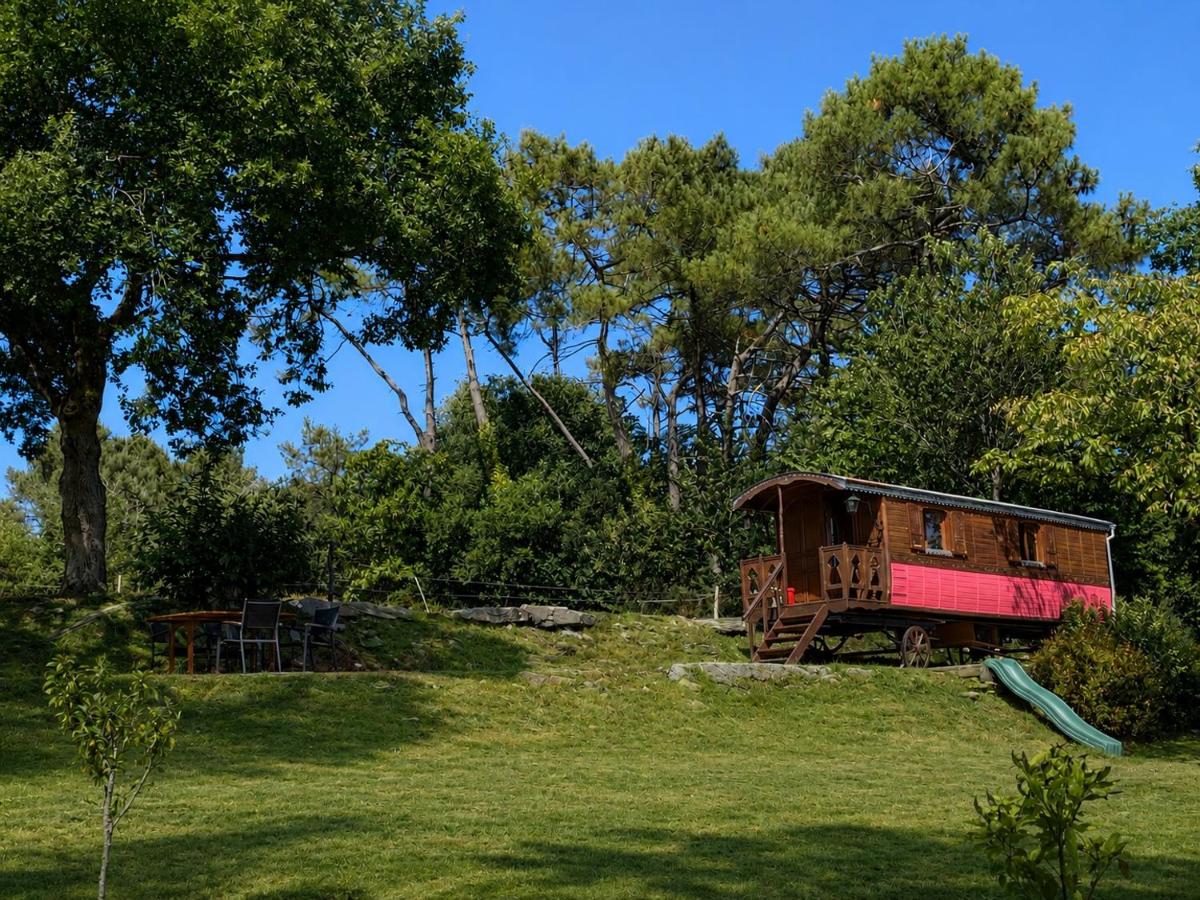 Brown wooden roulotte with pink lower panels sits at dog-friendly Une Roulotte et Des Chevaux in Sulniac.