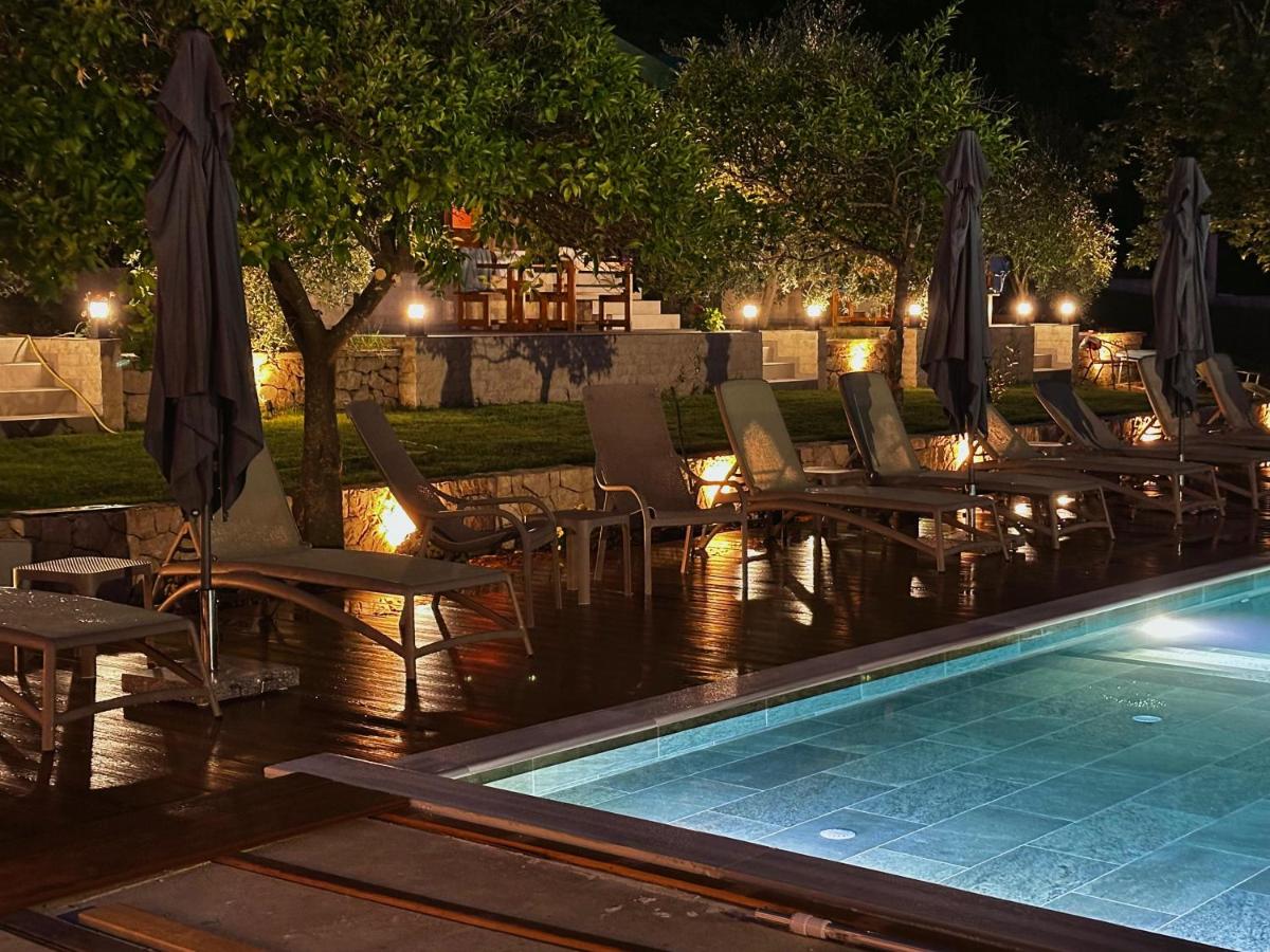 Brown lounge chairs with closed dark umbrellas are lined up at dog-friendly Casa Mila Apartments & Bungalows in Ulcinj.