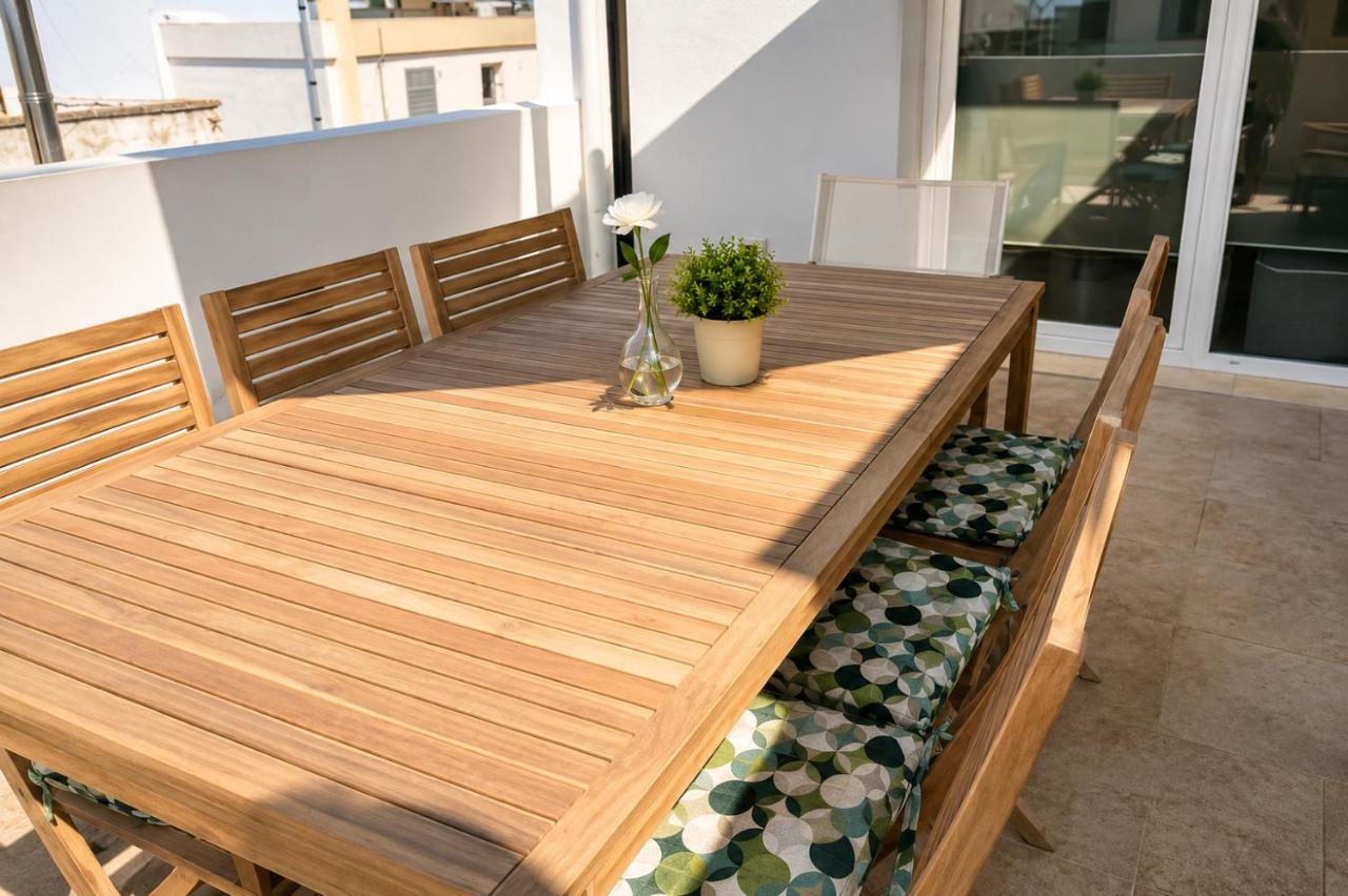 Wooden table with green patterned cushions and white flower sits at dog-friendly B&B EVO Nardò in Nardo.