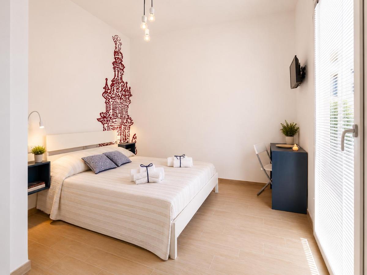 White bed with beige striped cover and two blue pillows sits near window at pet-friendly B&B EVO Nardò in Nardo.