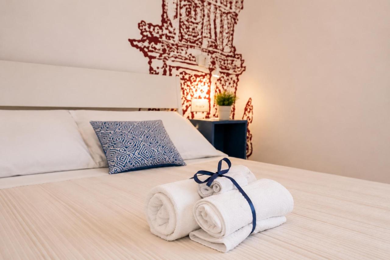 White rolled towels with navy ribbon rest on beige bed at dog-friendly B&B EVO Nardò in Nardo.