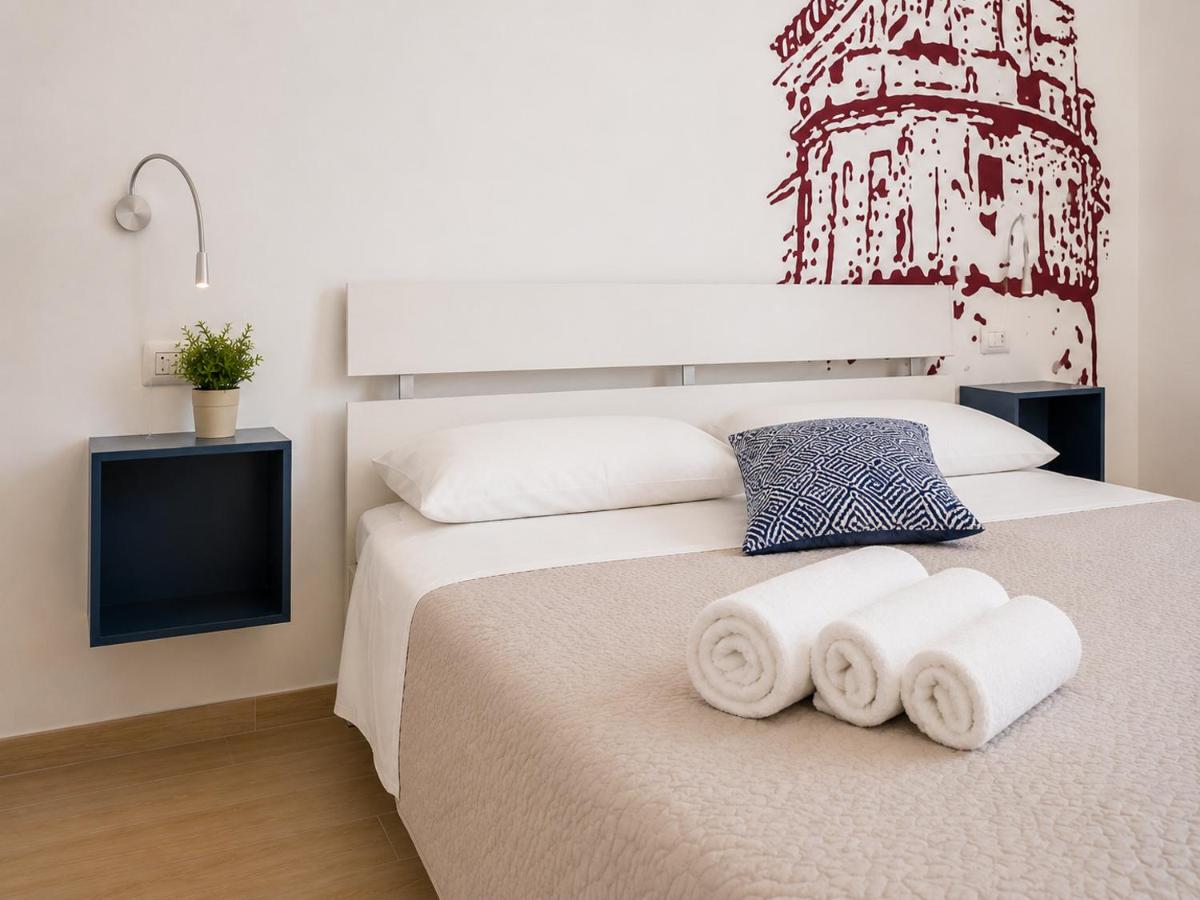 Beige bed with white pillows and three rolled white towels sits at dog-friendly B&B EVO Nardò in Nardo.