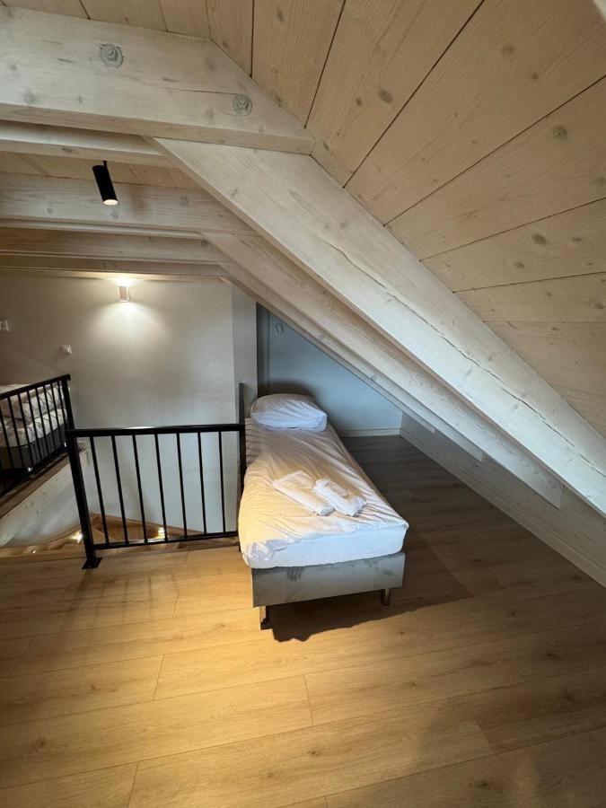 Single bed with white sheets and pillow under sloped wooden ceiling sits at dog-friendly Port Rewa in Rewa.