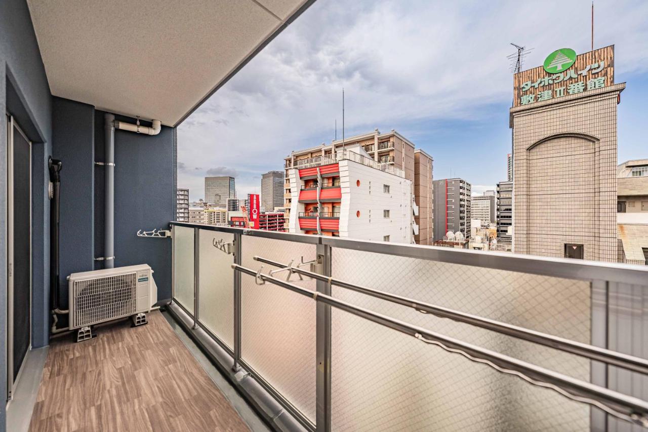 Blue-walled balcony with wood-patterned floor overlooks city at pet-friendly Apartment Hotel 11 Namba Minami in Osaka.