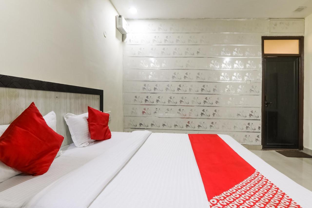 White bed with red pillows and red runner is made at dog-friendly Hotel O Samrat in Kanpur.