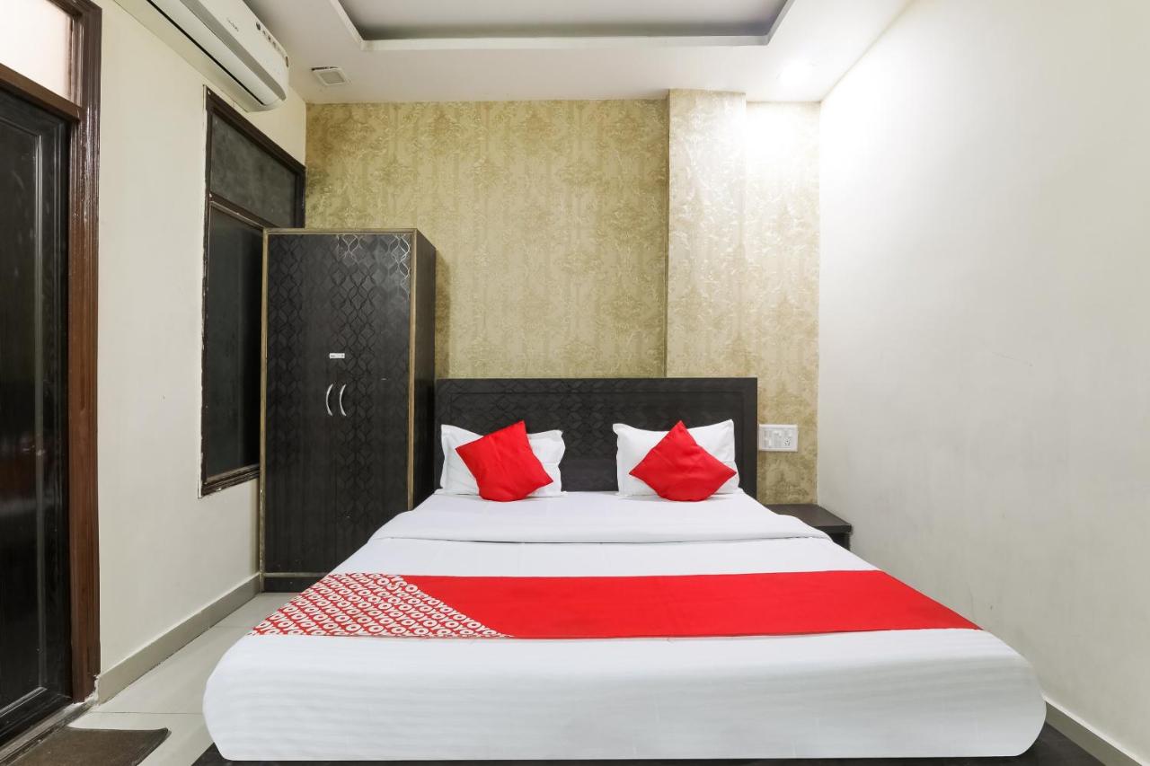 White bed with red runner and red pillows is centered at dog-friendly Hotel O Samrat in Kanpur.