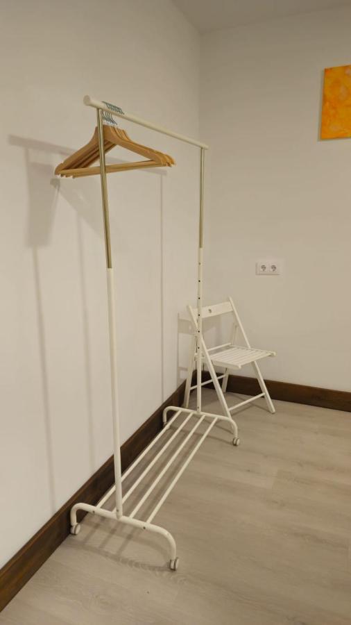 White metal clothing rack with wooden hangers stands at pet-friendly JABUTI Autocaravana Con Porche Y Aparcamiento in El Palmar.